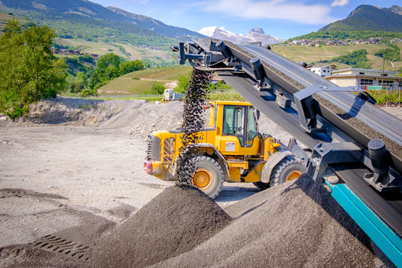 Chargeuse alimentant un concasseur face aux montagnes